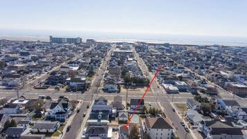 An aerial view of a residential area with houses, streets, and a beach in the background.