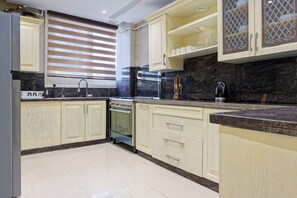 A modern kitchen with light-colored cabinets, a built-in oven, a stove, and a coffee maker. - VESTA  - Luxury APT - 4BR - New Cairo (III) (New Cairo City)