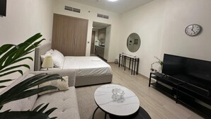 A modern bedroom with a bed, bedside table, and a TV. - VESTA - Luxury Studio - Riviera (I) (Dubai)