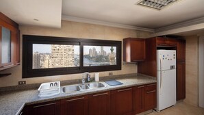 A kitchen with a window view, a sink, a refrigerator, and wooden cabinets. - VESTA  - Luxury APT - 4BR - Agouza (I) (Giza)