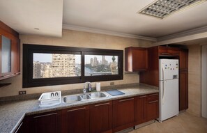 Eine Küche mit Blick aus dem Fenster, einem Spülbecken, einem Kühlschrank und Holzschränken.