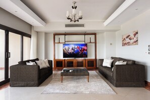Ein modernes Wohnzimmer mit Flachbildfernseher, zwei Sofas, einem Couchtisch und einer Deckenleuchte.