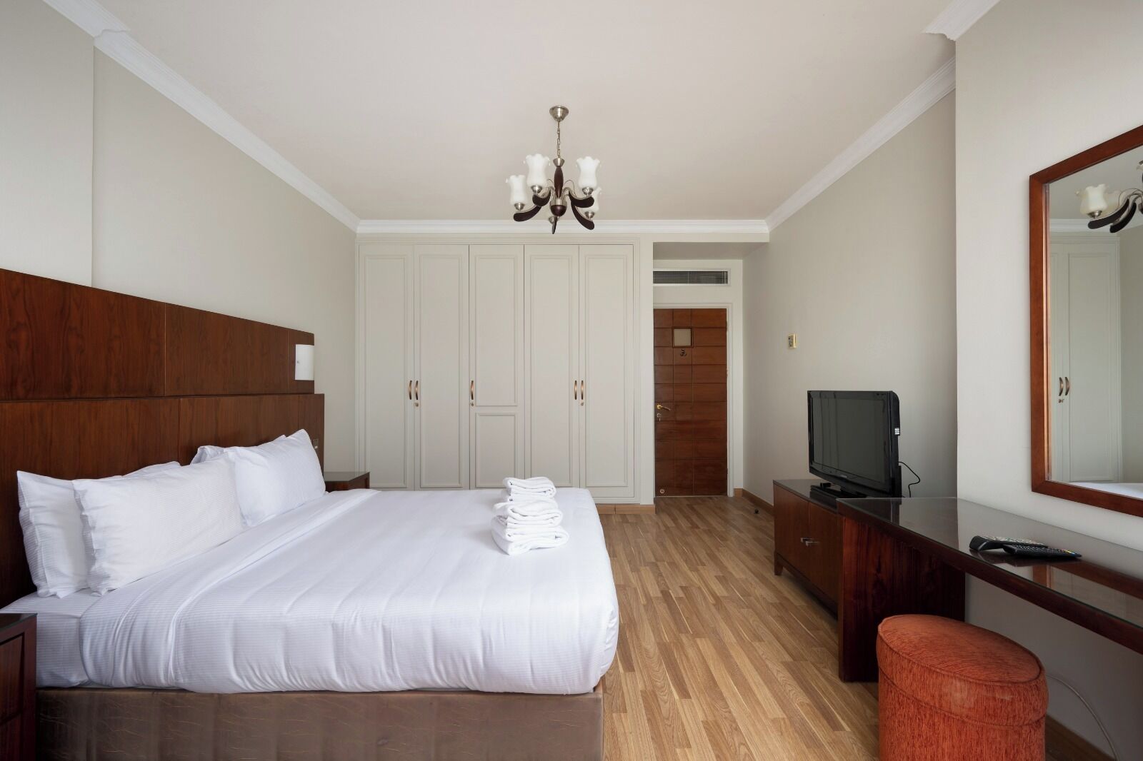 A hotel room with a large bed, a TV, a desk, and a mirror.