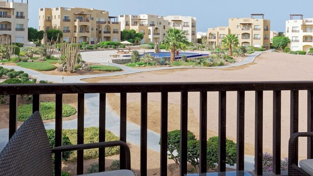 Un balcon donnant sur un complexe hôtelier, avec vue sur les bâtiments et la piscine.