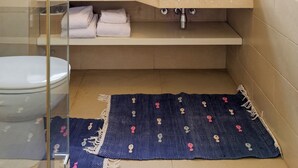 Une salle de bain avec une douche à parois de verre, un lavabo avec un miroir au-dessus et une fenêtre.