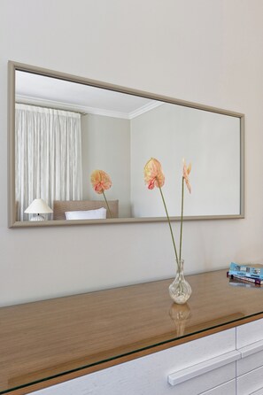 A room with a large mirror, a bedside table, a lamp, and a vase with flowers. - VESTA  - Luxury APT - 3BR - South Teseen (III) (New Cairo City)