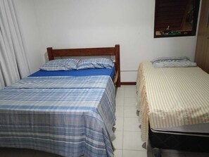 Ein Schlafzimmer mit zwei Betten, eines mit blau-weiß karierter Bettdecke und das andere mit einer Streifenoptik.
