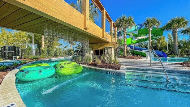 Un espace piscine doté d’une terrasse en bois, d’un toboggan et de bouées gonflables.