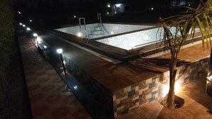 Un espace extérieur avec piscine, accessible la nuit, doté d’une terrasse carrelée, d’une petite piscine et d’un palmier.