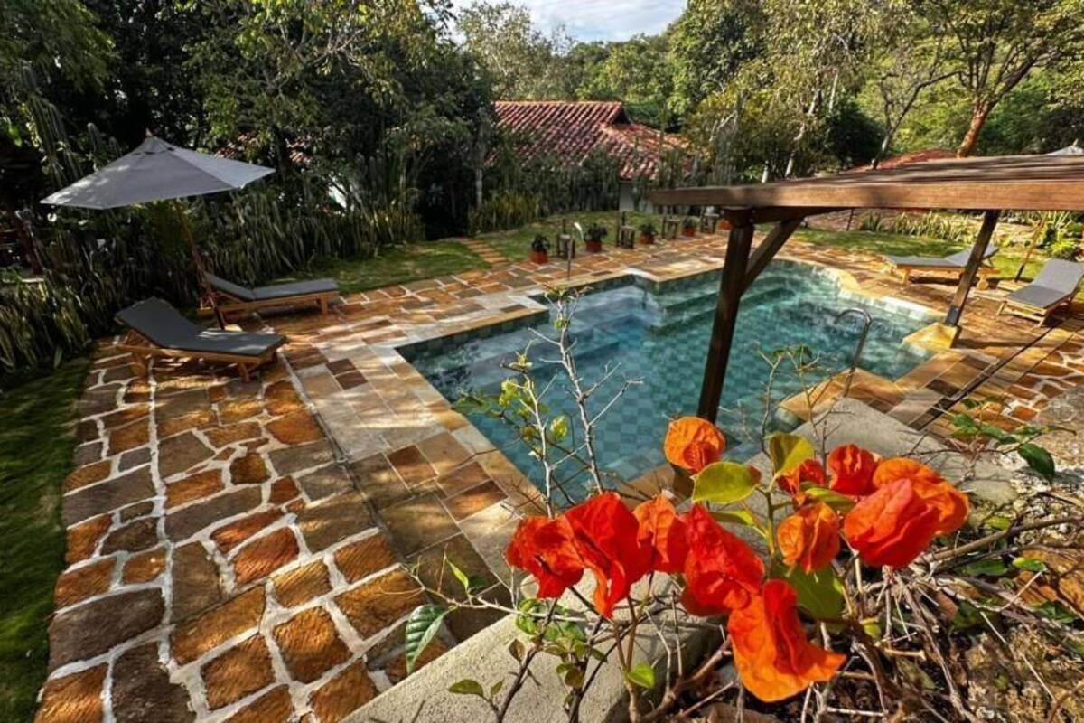 A swimming pool with a stone deck, lounge chairs, and a pergola.