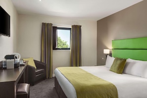 A hotel room with a bed, a desk, a chair, a television, and a window with curtains. - Oldbury Birmingham (Oldbury)