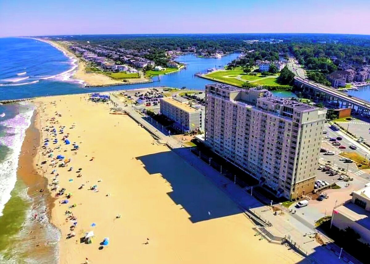 A coastal hotel with a beach, a parking lot, and a river.