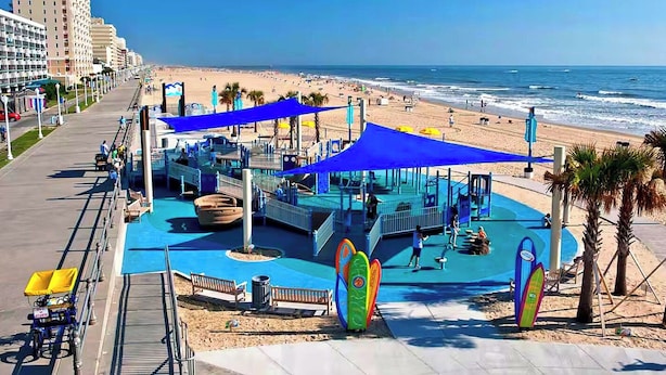 A beachside playground with blue canopies, a pool, and surfboard decorations. - Luxury Oceanfront 2BR 2BA Condo Private Balcony Beach Pool Full Kitchen Gym (Virginia Beach)