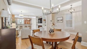 A dining area with a round wooden table, six chairs, a chandelier, and a vase with flowers. - Annapolis Gem- Tranquil 4 BR Murray Hill Victorian (Annapolis)