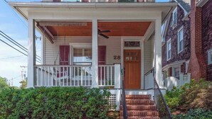 A two-story house with a porch, a wooden door, and a stone wall in front. - Annapolis Gem- Tranquil 4 BR Murray Hill Victorian (Annapolis)
