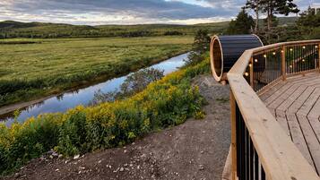A wooden deck with a view of a river and distant hills.