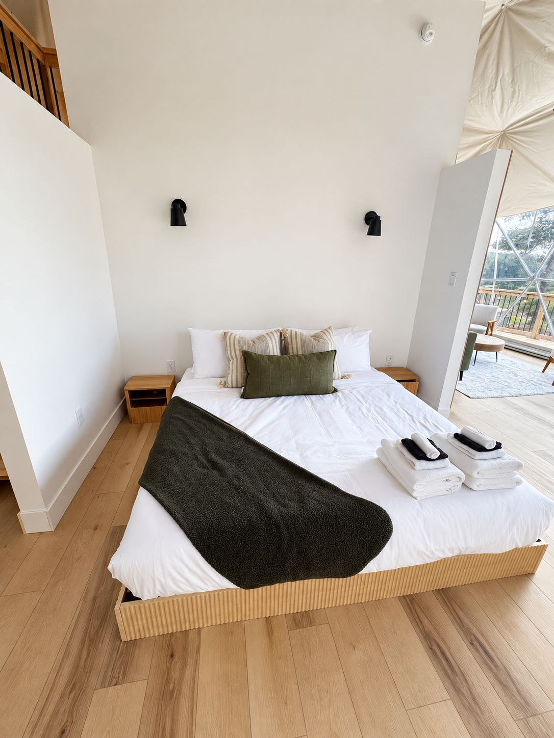 A spacious bedroom with a large bed, wooden flooring, and a view of the outdoors.