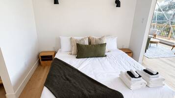 A spacious bedroom with a large bed, wooden flooring, and a view of the outdoors.