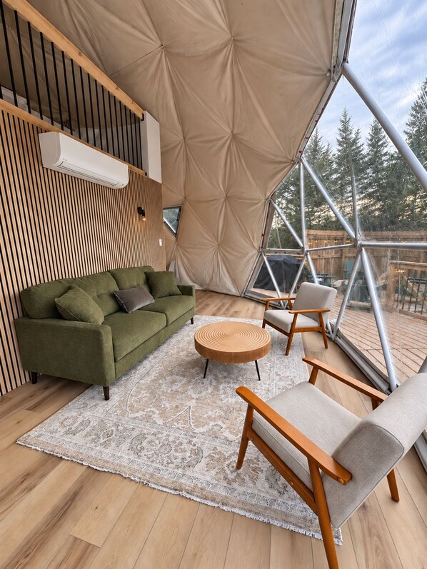 A cozy interior with a green sofa, a round wooden table, and a wooden chair.