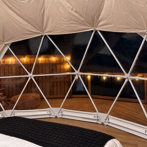 Eine zeltähnliche Konstruktion mit einer Holzterrasse und Lichterketten.