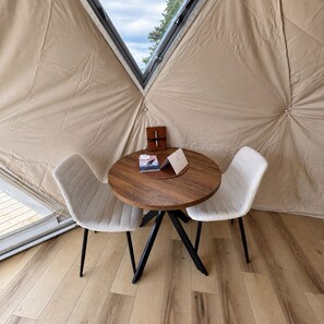 A tent with a round table and two chairs, a wooden box, and a booklet on the table. - The Falls - The Intimate Dome at Granda Rose Retreat (Branch)