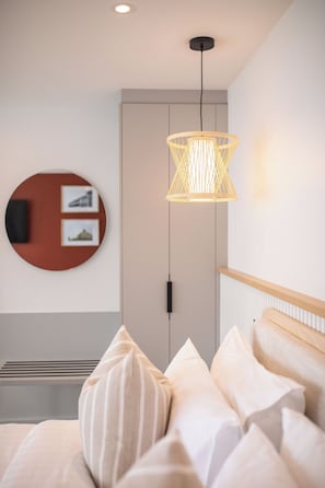 A modern bedroom with a bed, a circular wall art piece, a pendant light, and a wooden headboard.