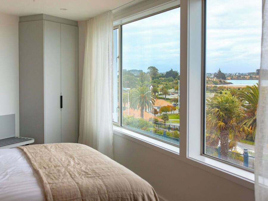 A bedroom with a large window, a bed, a wardrobe, and a radiator.