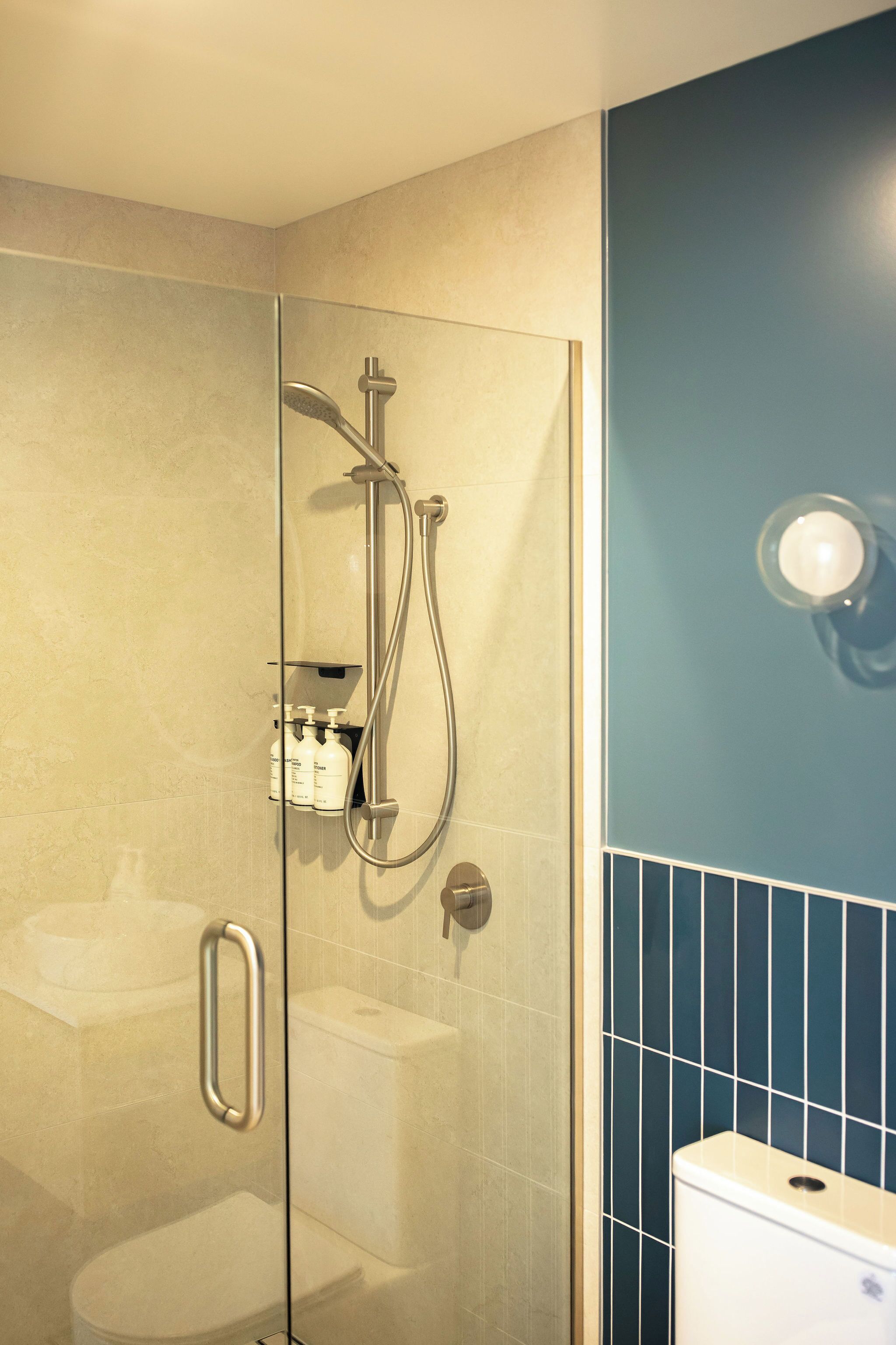Une salle de bain avec une douche à parois de verre, des toilettes et un lavabo.
