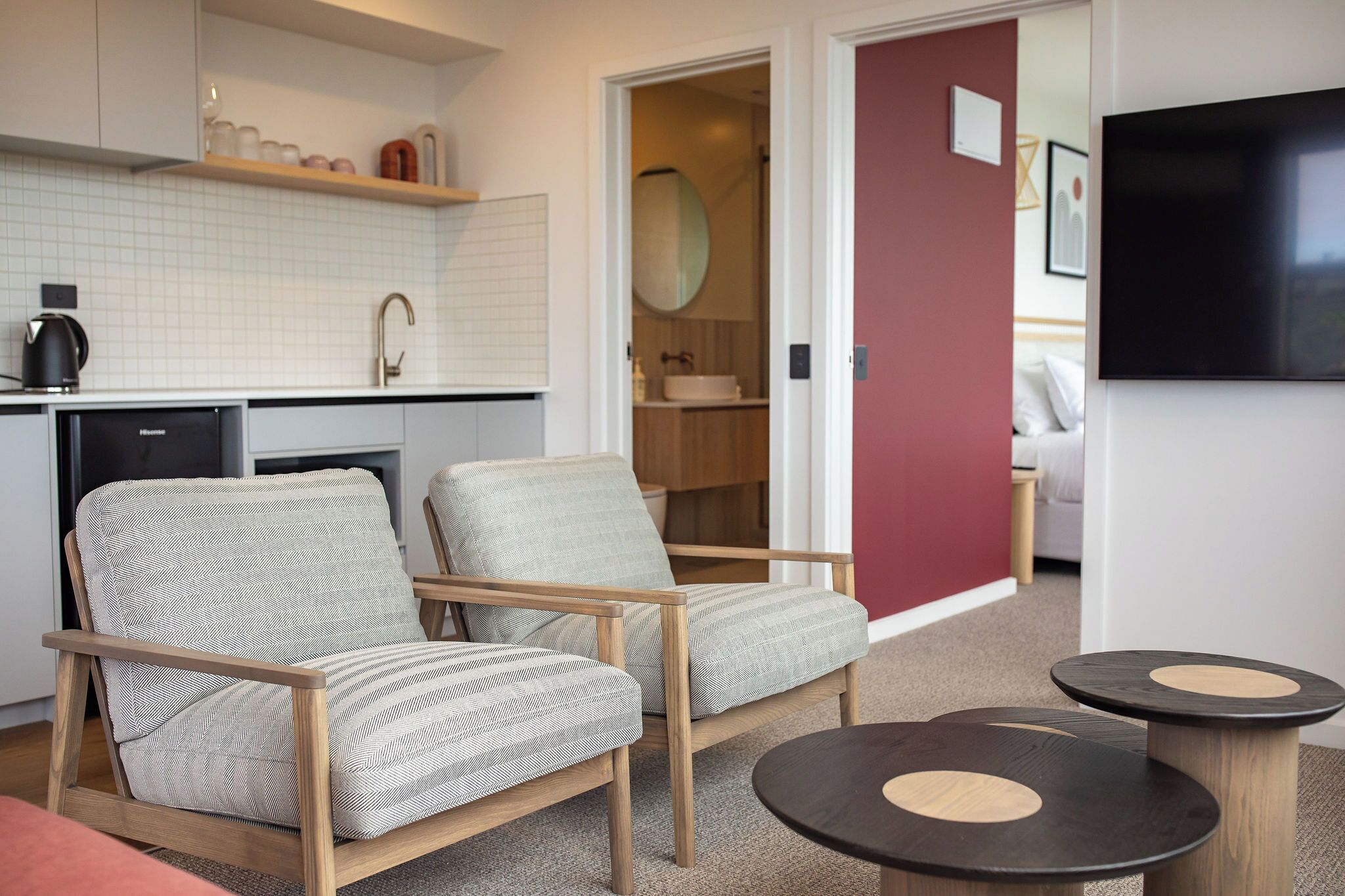 A modern living room with two armchairs, a coffee machine, a TV, and a small table.