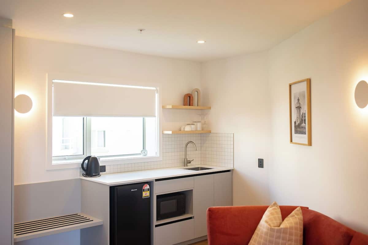 A compact kitchen with a window, built-in microwave, and a small refrigerator.