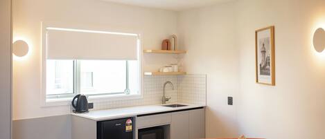 A compact kitchen with a window, built-in microwave, and a small refrigerator.
