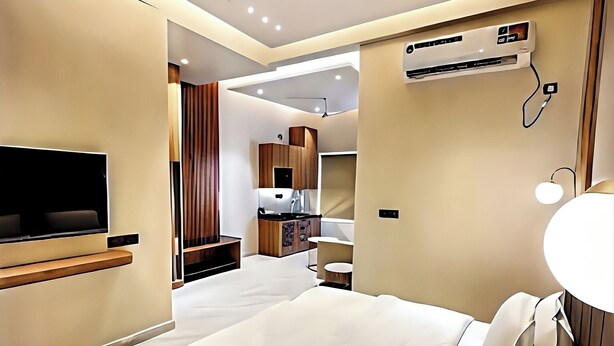 Een moderne hotelkamer met een groot bed, een flatscreen televisie, een plafondventilator en een airconditioning.