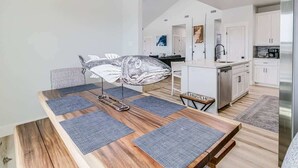 Eine moderne Küche mit weißen Schränken, Edelstahlgeräten und einem Essbereich mit Holztisch und Stühlen.