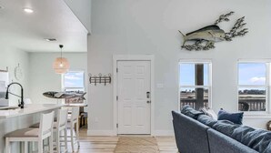 Eine moderne Küche mit weißen Barhocker, einem großen Fenster und Blick ins Freie.