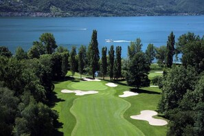 Ein Golfplatz mit Sandbunkern, einem Wasserhindernis und Bäumen.
