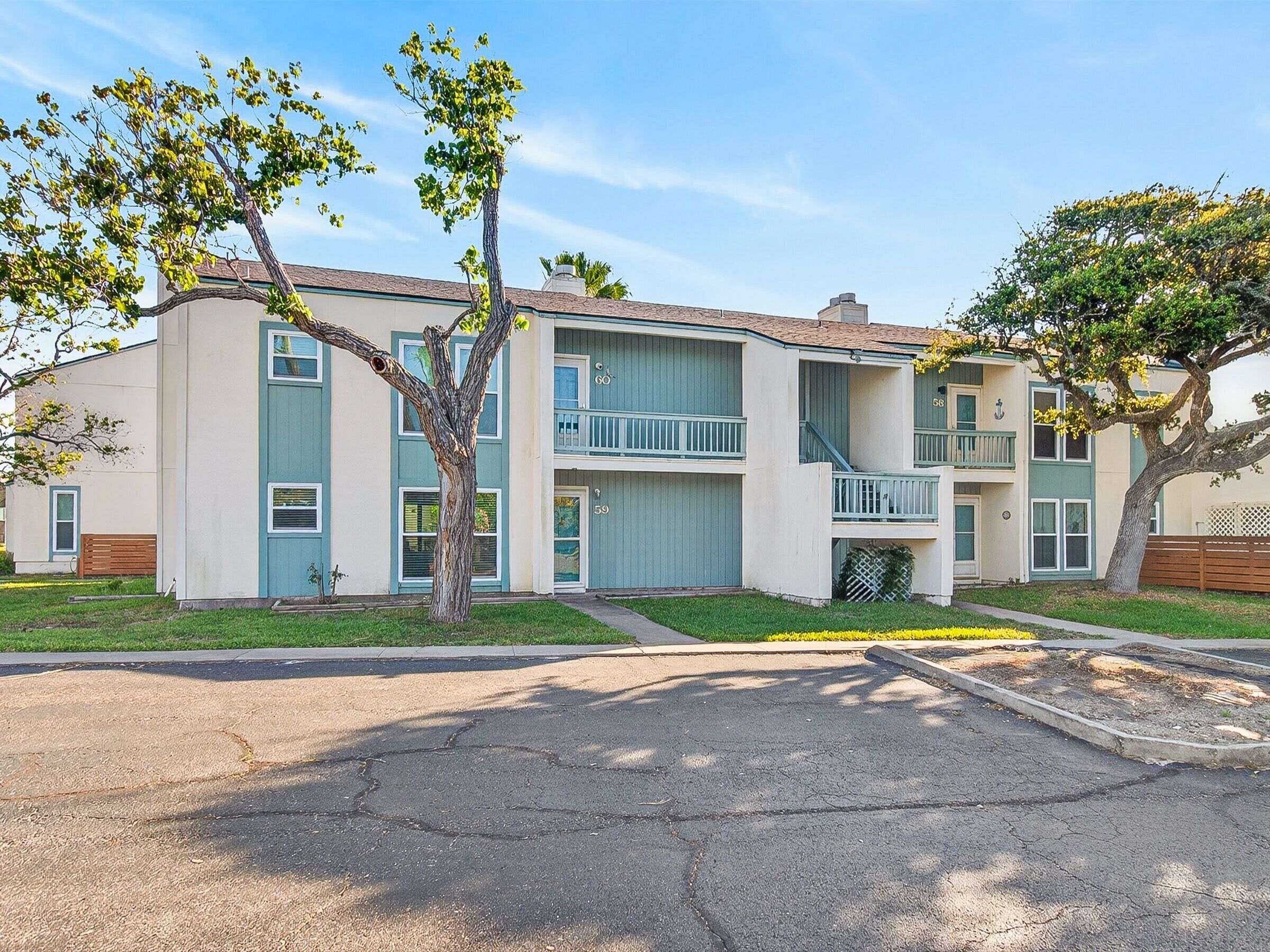 A multi-story residential building with a central staircase, balconies, and a well-maintained lawn.