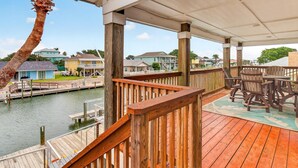 Um deck de madeira com vista para uma marina e casas ao fundo.