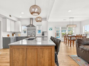 A modern kitchen with a central island, wooden cabinets, and pendant lighting. - The Redfish Palm -  Rockport, Texas (Rockport)