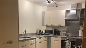A compact kitchen with a dining table, a microwave, a stove, and a trash bin. - 1 bed & 1 bath apartment large balcony - 10 min walk from new street station (Birmingham)