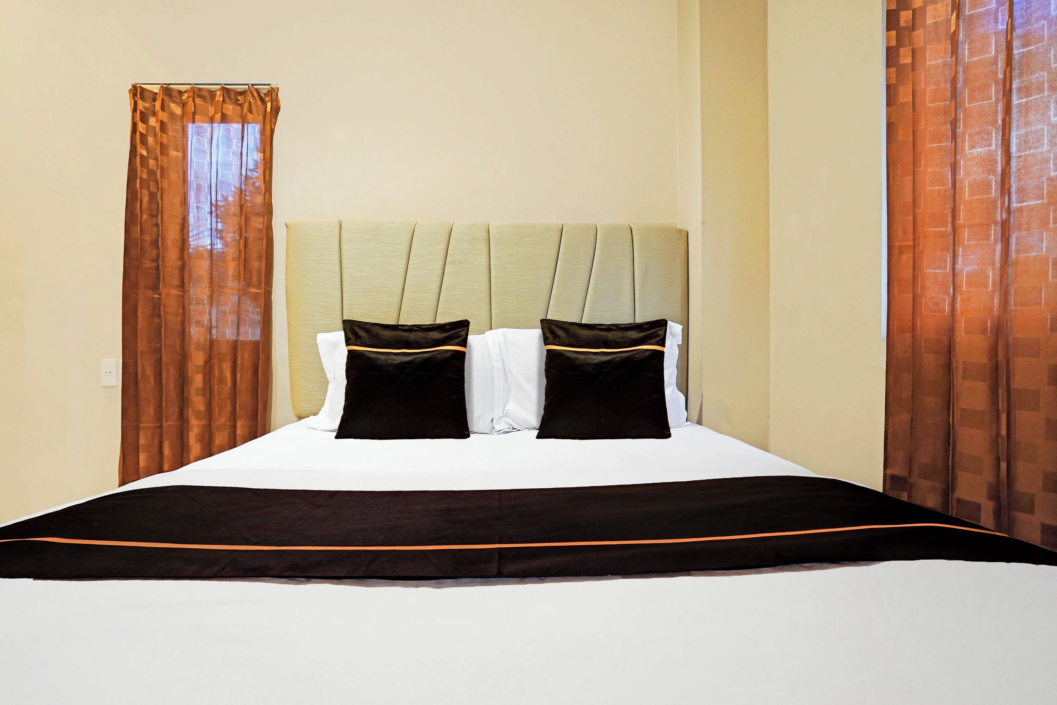 A hotel room with a bed, curtains, and a headboard.