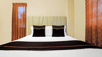 Una habitación de hotel con cama, cortinas y cabecera.