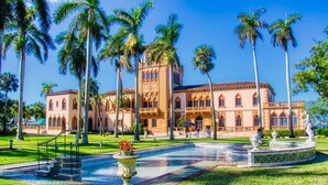 A large building with a symmetrical facade, palm trees, and a central fountain. - The Lovely Gem 6 miles to Siesta Key Paradise (Sarasota)