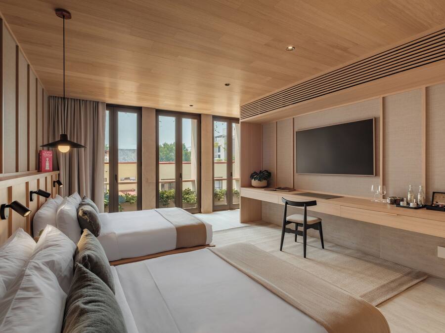 Une chambre d’hôtel moderne, dotée d’un grand lit, d’un bureau, d’une télévision et offrant une vue sur l’extérieur.