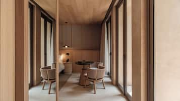 Un interior moderno con techo de madera, ventanas amplias, una mesa redonda y dos sillas.