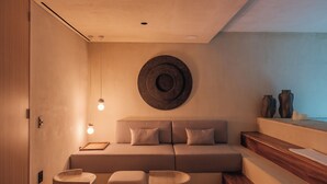 A modern interior with a sofa, ottomans, a wall-mounted circular object, and a wooden staircase.
