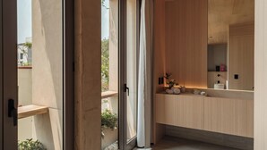 A modern bathroom with a large mirror, wooden vanity, and a sliding glass door leading to a balcony.