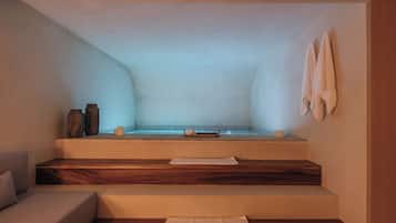Un cuarto de spa con una bañera, escalones de madera, una toalla y jarrones decorativos.
