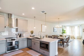 A modern kitchen with stainless steel appliances, a dining area with a table and chairs, and a living room with a sofa and a plant. - Apple Nextdoor. Tech corridor (Austin)