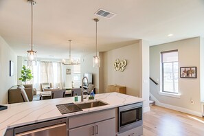 A modern kitchen with a large island, stainless steel appliances, pendant lighting, and a view to the living area. - Apple Nextdoor. Tech corridor (Austin)