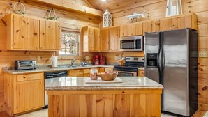 A kitchen with wooden cabinets, a stainless steel refrigerator, a microwave, a stove, and a toaster. - NEW CABIN!-Pet Friendly-Babbling Brook-Private Lake-Grill (Lake Lure)